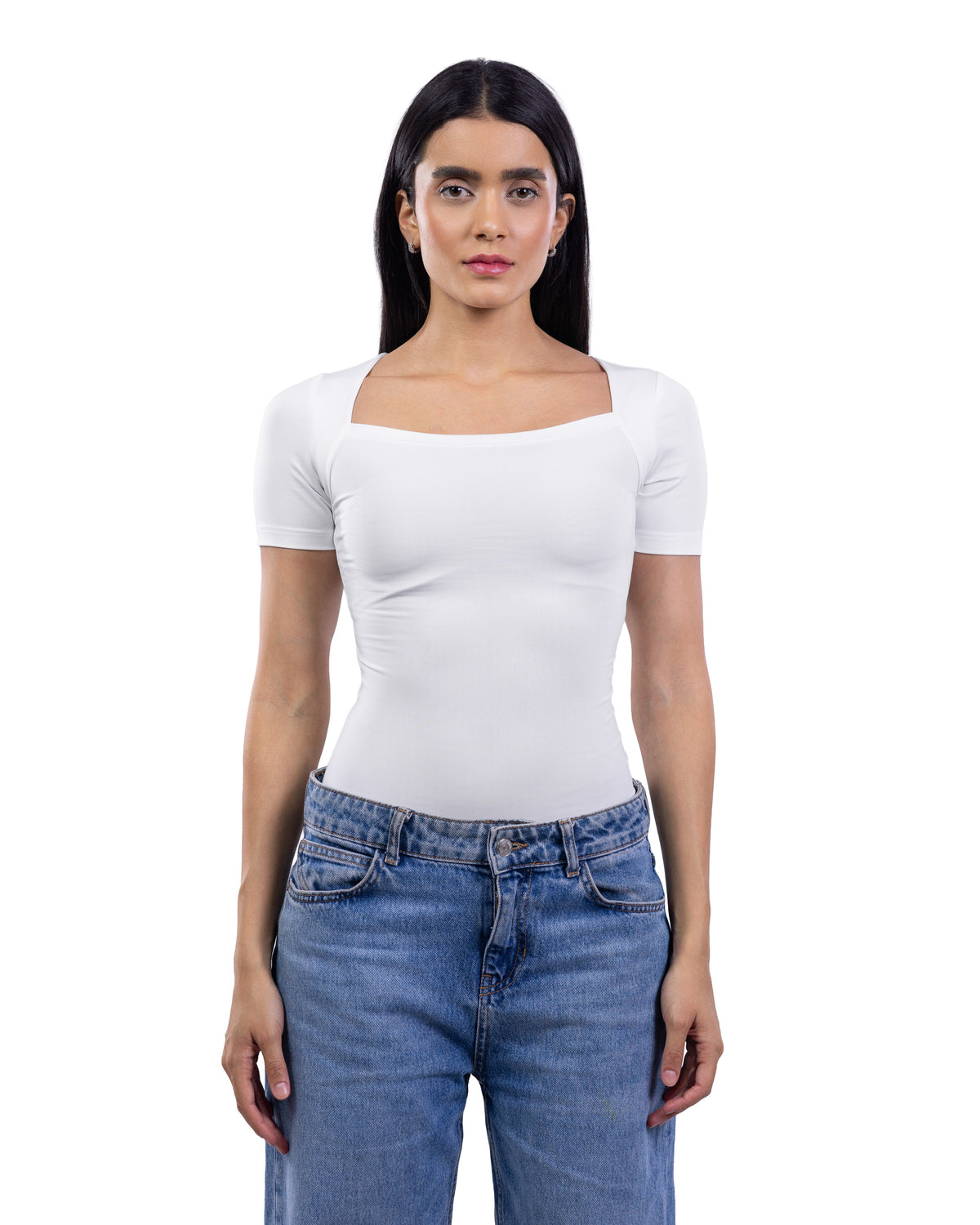 A woman modeling a fitted white short-sleeve top with a square neckline, paired with blue jeans, against a plain white background.