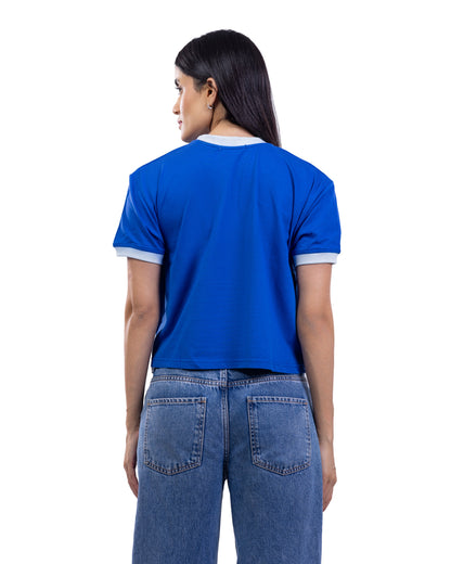 A woman shown from the back wearing a bright blue short-sleeve ringer T-shirt with white trim on the collar and sleeve cuffs, paired with blue jeans, against a plain white background.