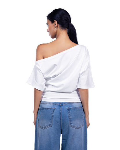 A woman shown from the back wearing a white draped off-the-shoulder top and blue jeans against a plain white background.