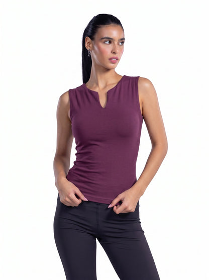 A woman modeling a sleeveless, deep plum-purple athletic top with a split neckline, paired with black leggings, against a solid white background.
