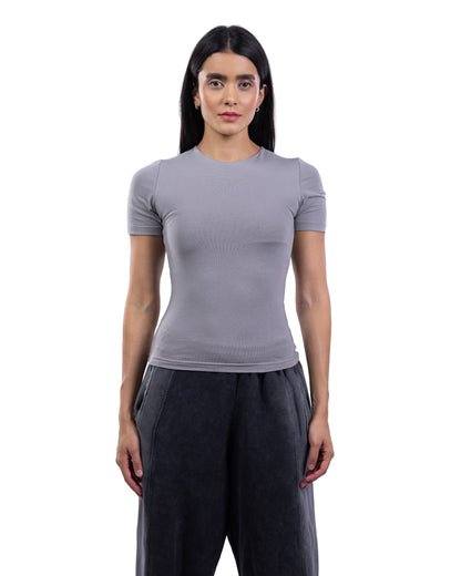 A woman modeling a fitted short-sleeve crewneck top in light gray, paired with dark gray wide-leg pants, against a plain white background.