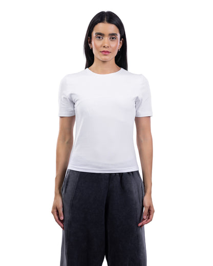 A woman modeling a plain white short-sleeve crewneck t-shirt paired with dark charcoal gray wide-leg pants, shot against a seamless white background.