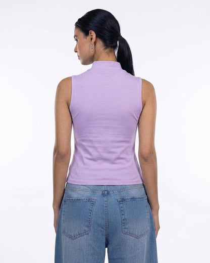 A woman shown from the back wearing a sleeveless lavender mock neck top and blue jeans against a plain white background.