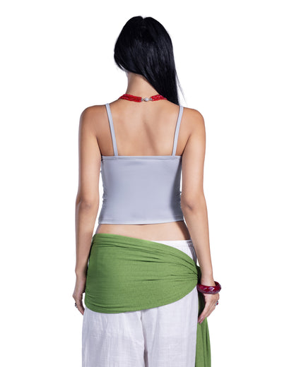 A woman shown from the back wearing a light gray spaghetti-strap crop top, white pants, and a green fabric wrap, against a plain white background.
